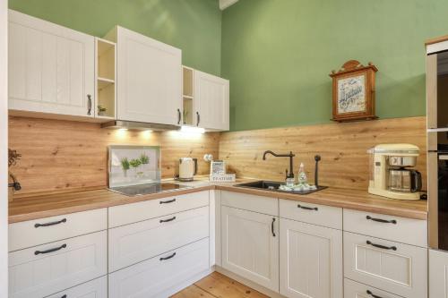 a kitchen with white cabinets and a clock on the wall at Ferienwohnungen Steinweg 61 in Quedlinburg