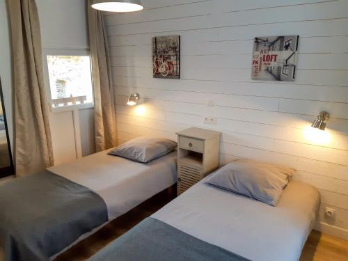 two twin beds in a room with two lamps at Gite Lodge Le 1900 in Val Couesnon