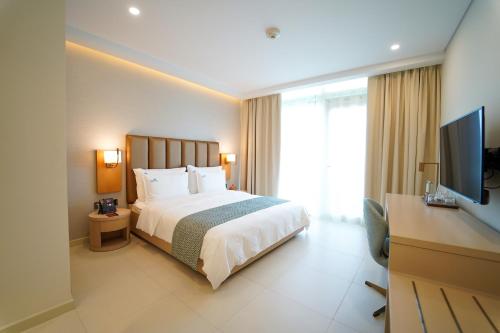 a hotel room with a bed and a flat screen tv at Zoya Health & Wellbeing Resort in Ajman