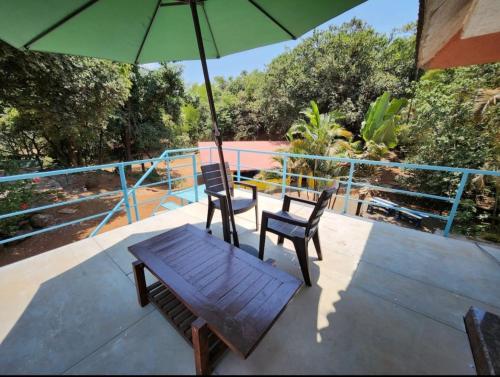a patio with two chairs and a table and an umbrella at Captans Stay in Lonavala