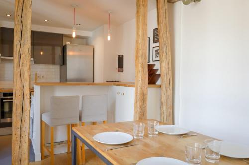 Il dispose d'une cuisine avec une table en bois et des plaques blanches. dans l'établissement Appartement Chic & Spacieux | Paris 2ème, à Paris