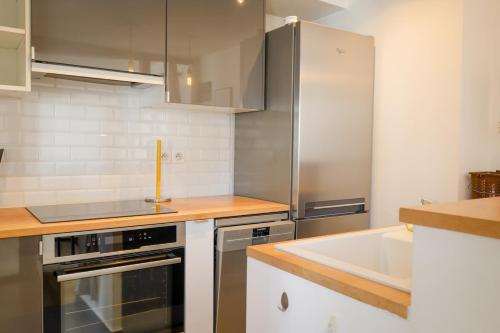 une cuisine avec un réfrigérateur en acier inoxydable et un évier dans l'établissement Appartement Chic & Spacieux | Paris 2ème, à Paris