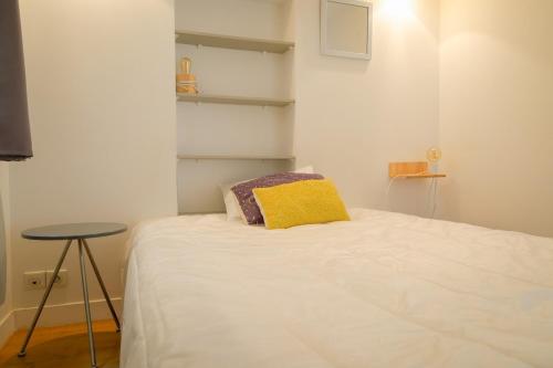 - une chambre avec un lit doté d'un oreiller jaune et d'une table dans l'établissement Appartement Chic & Spacieux | Paris 2ème, à Paris