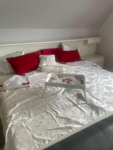 a white bed with red pillows and a table on it at Sonniges Studio in Rheine Nähe Zentrum in Rheine