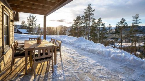 a table and chairs on a porch in the snow at Gandalv Hytte - 8p - With Sauna & Hot Tub in Vradal