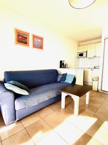 un salon avec un canapé bleu et une table dans l'établissement Appartement vue mer, terrasse, place de parking privée, proximité des commerces, à Saintes-Maries-de-la-Mer