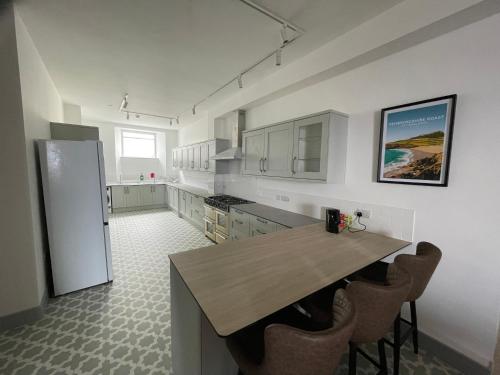 a kitchen with a wooden table and a refrigerator at Abergwaun Cottage in Fishguard