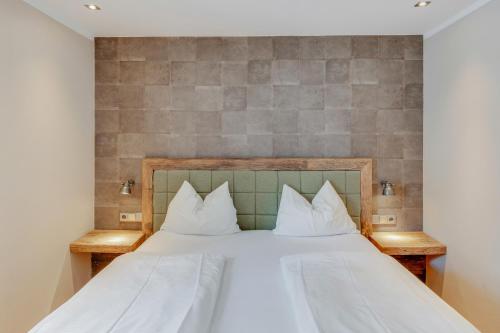 a bedroom with a bed with white sheets and pillows at Design Apartment Villa Anna Kitzbühel in Kitzbühel