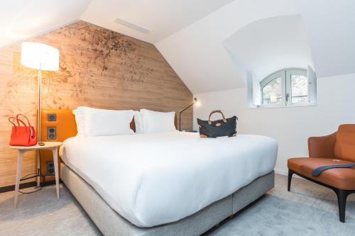 a bedroom with a large white bed and a chair at Dolce by Wyndham Versailles - Domaine du Montcel in Jouy-en-Josas