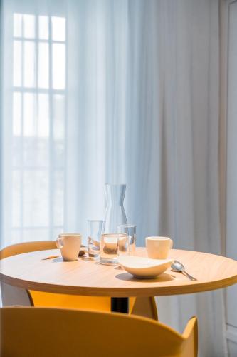 a wooden table with two glasses and a vase on it at Dolce by Wyndham Versailles - Domaine du Montcel in Jouy-en-Josas