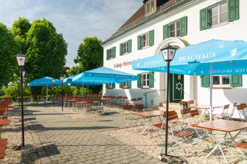 a patio with tables and blue umbrellas in front of a building at Hotel Restaurant Taverna in Eching