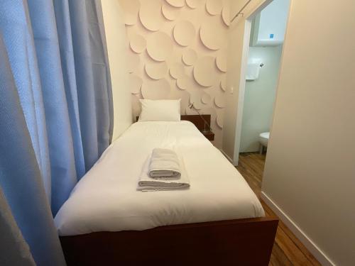 a small bedroom with a white bed with blue curtains at Tavarn Ty Gar in Hennebont