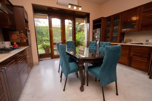 a kitchen with a wooden table and blue chairs at Elevé Villa in Karachi