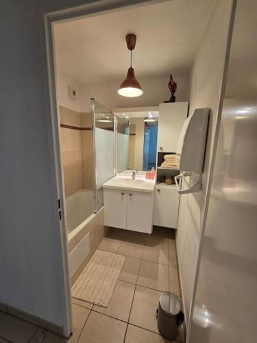 une salle de bain avec un lavabo, une baignoire et un miroir dans l'établissement Super appartement familial Disneyland Paris 5pers, à Bussy-Saint-Georges