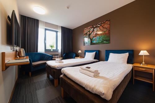 a hotel room with two beds and a couch at Comfort Hotel Kuldiga in Kuldīga