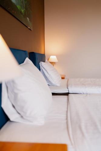 two beds in a hotel room with white pillows at Comfort Hotel Kuldiga in Kuldīga