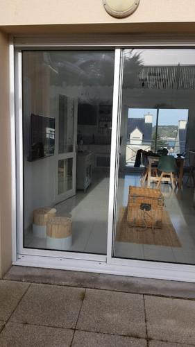 a sliding glass door of a house with a room with a table at Erquy, vue mer, centre, plages & commerces a pieds in Erquy