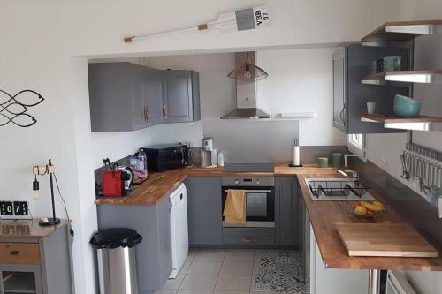 a small kitchen with wooden counter tops and cabinets at Erquy, vue mer, centre, plages & commerces a pieds in Erquy