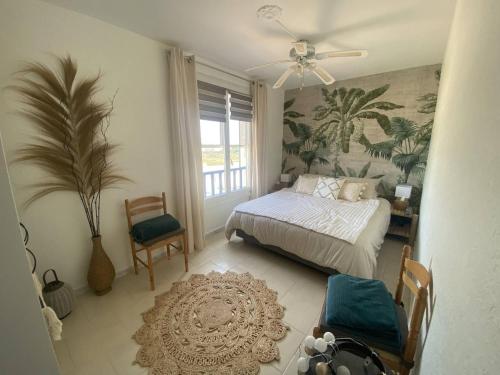 - une chambre avec un lit, une fenêtre et un ventilateur dans l'établissement Appartement sur la plage - parking - terrasse vue mer - 1er étage, à Saintes-Maries-de-la-Mer