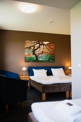 two beds in a room with a painting on the wall at Comfort Hotel Kuldiga in Kuldīga