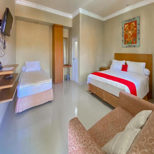 a hotel room with two beds and a couch at RedDoorz near Taman Bunga Nusantara in Pasirhuni