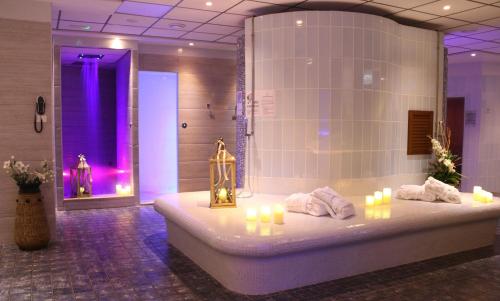 a bathroom with a tub with candles and a shower at Cocca Hotel Royal Thai Spa in Sarnico