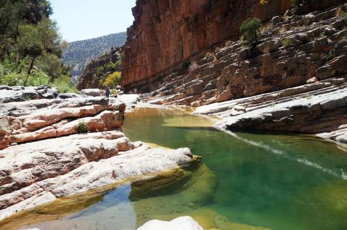 a pool of water in a canyon with rocks at The Lunar Surf House in Tamraght Ouzdar