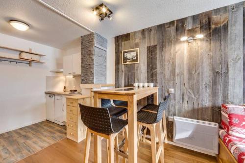 a kitchen with a wooden wall with a table and chairs at Jardins de Val Le charme à la Montagne in Val dʼIsère