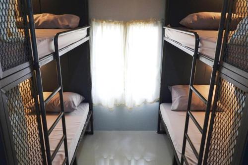 zwei Etagenbetten in einem Zimmer mit Fenster in der Unterkunft Urban Bed in Chiang Mai