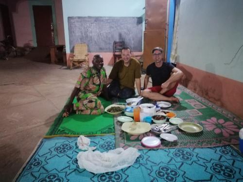 a group of three men sitting around a table with food at CHEZ ALFA in Djougou