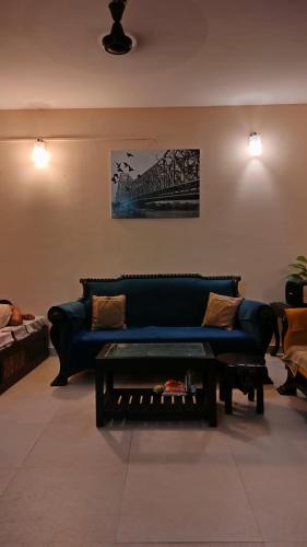 a living room with a blue couch and a coffee table at Luxury Villa Ganga Kutir in Raichak