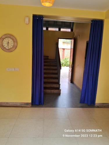 a hallway with blue curtains and stairs with a clock at Luxury Villa Large Private Pool in Raichak
