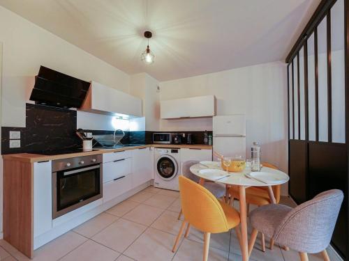 une cuisine avec une table et des chaises dans une cuisine dans l'établissement L'Alba Rosso - Climatisation, parking et terrasse, à Castelnau-le-Lez