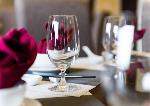 two wine glasses sitting on a table with roses at Muong Thanh Grand Ha Tinh Hotel in Kỳ Anh