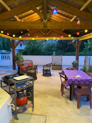 a patio with a table and chairs under a wooden pergola at La Maison du Parloir in Queaux