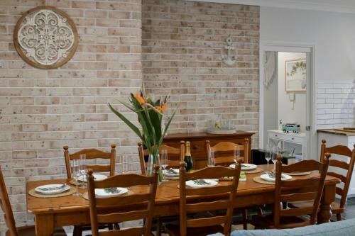 a dining room with a wooden table and a brick wall at 7Palms Retreat at Jervis Bay in Vincentia