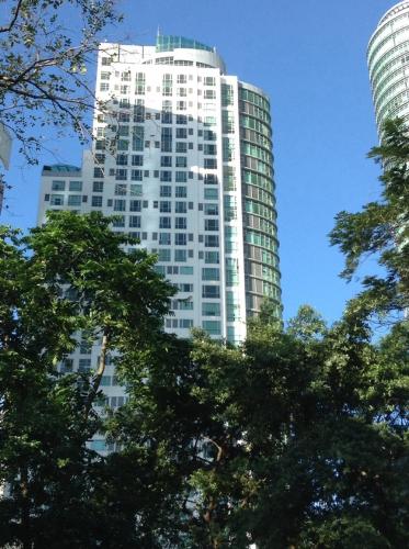 a tall white building with trees in front of it at Avant Apartments at The Fort in Manila