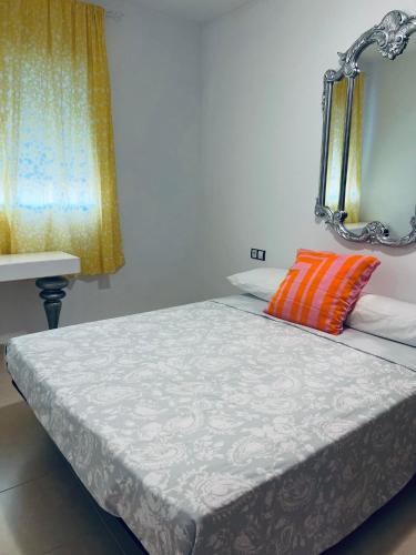 a bed with an orange pillow and a mirror at Casa Capri in Torre-Guil