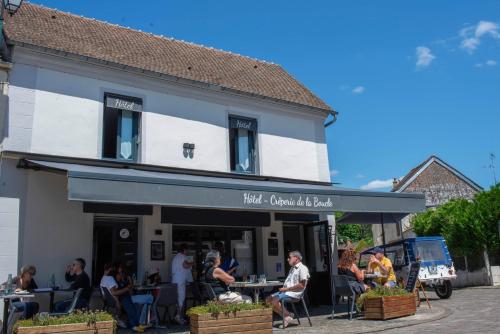 a group of people sitting at tables outside of a building at Auberge de la boucle in Moisson