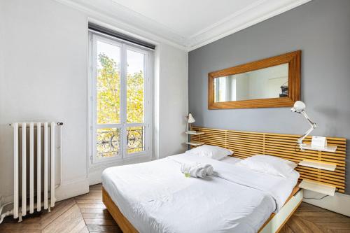 une chambre avec un lit, un miroir et une fenêtre dans l'établissement GuestReady - Séjour Cosy Familial pour 4, à Paris