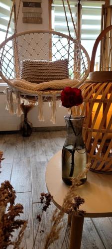 un vase avec une rose assise sur une table dans l'établissement Cottage Interieur Spa classé 4 étoiles - balnéo et sauna privatif, à Tannay