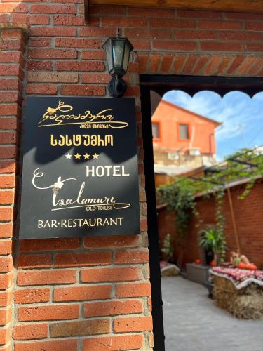 a sign for a hotel on a brick wall at Tsalamuri Old Tbilisi in Tbilisi City