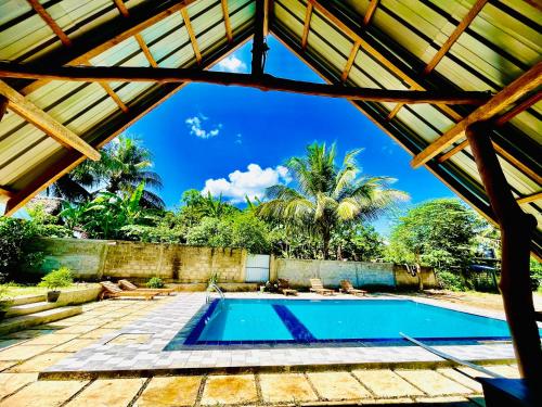 a swimming pool in a house with a wooden roof at Udawalawa Safari House in Udawalawe