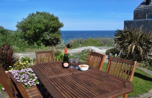 a wooden table with a bottle of wine and a drink at Morning Cottage in St Ives