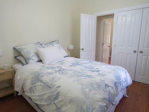 a bedroom with a bed with a blue and white blanket at The Homestead in Cable Bay