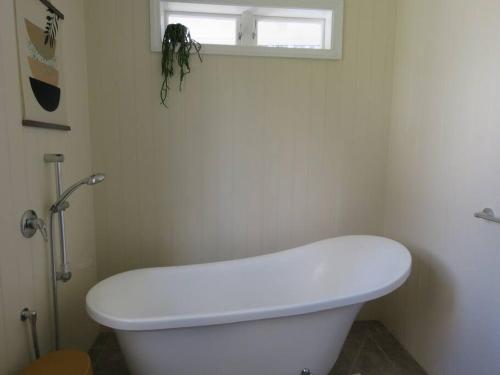 a white toilet in a bathroom with a window at The Homestead in Cable Bay