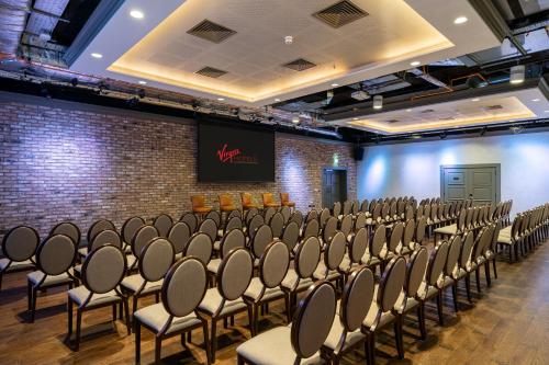a room with rows of chairs in a brick wall at Virgin Hotels London - Shoreditch in London