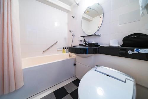 a bathroom with a toilet and a sink and a mirror at KOKO HOTEL Osaka Shinsaibashi in Osaka