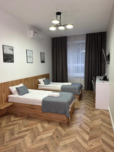 two beds in a room with wooden floors at Mastersclub in Ternopilʼ