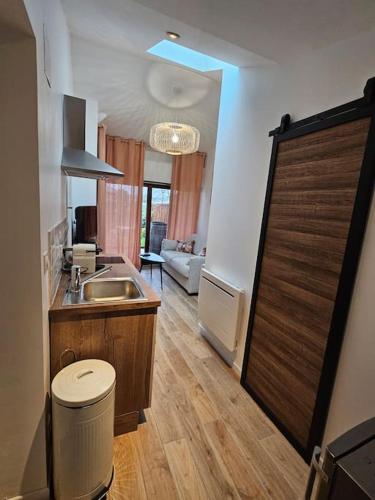 - une cuisine avec un évier et une porte en bois dans l'établissement logement avec cuisine et jardinet proche lac, à Soustons